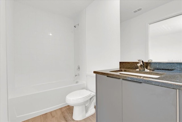 bathroom with toilet, wood finished floors, vanity, visible vents, and  shower combination