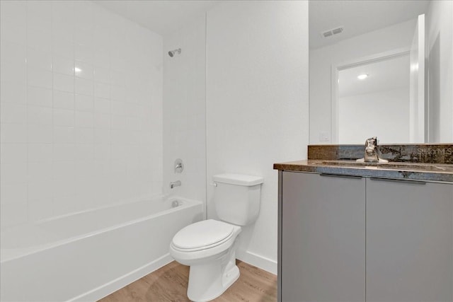 full bathroom with hardwood / wood-style flooring, tiled shower / bath combo, toilet, and vanity