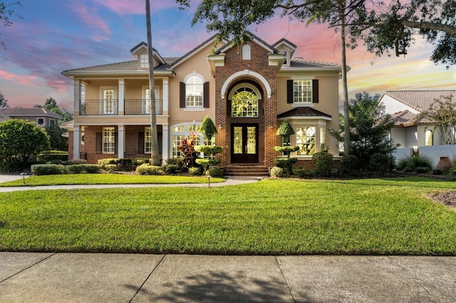 view of front of home with a yard and a balcony