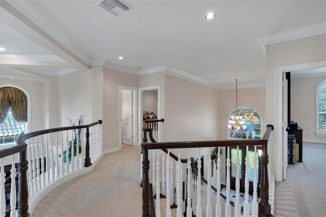 corridor featuring a notable chandelier, ornamental molding, and light colored carpet