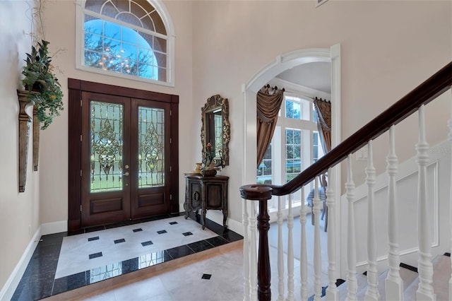 tiled foyer entrance with a towering ceiling and french doors