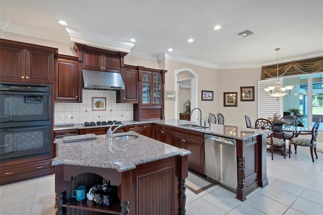 kitchen with appliances with stainless steel finishes, decorative light fixtures, tasteful backsplash, sink, and light stone counters