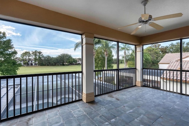 unfurnished sunroom featuring ceiling fan and a wealth of natural light