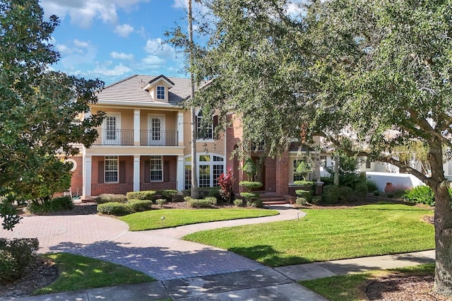 greek revival inspired property featuring a balcony and a front yard