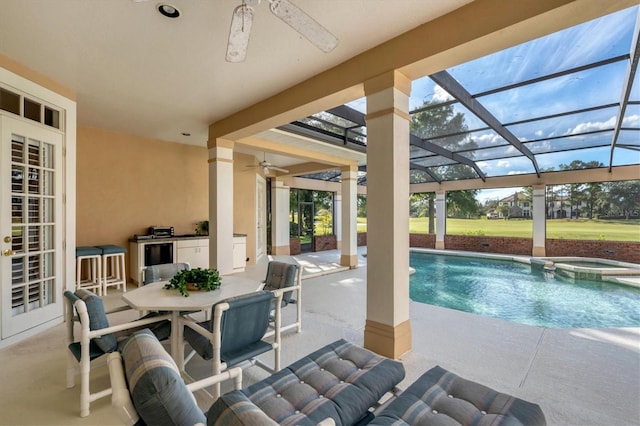 view of swimming pool with a patio, glass enclosure, an in ground hot tub, and ceiling fan