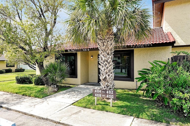 view of front of property with a tiled roof, a front lawn, and stucco siding