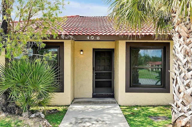 doorway to property with a tile roof and stucco siding