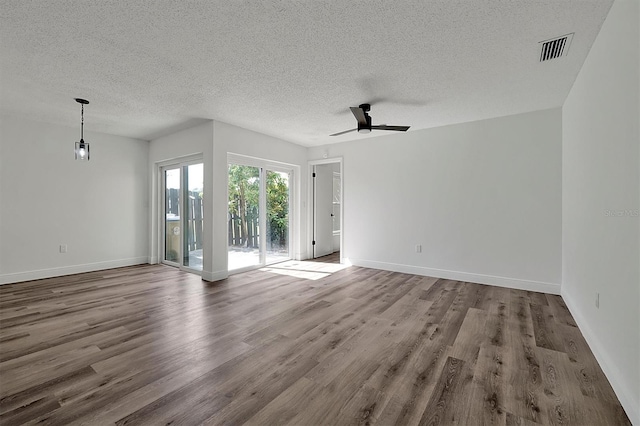 spare room featuring visible vents, ceiling fan, a textured ceiling, wood finished floors, and baseboards