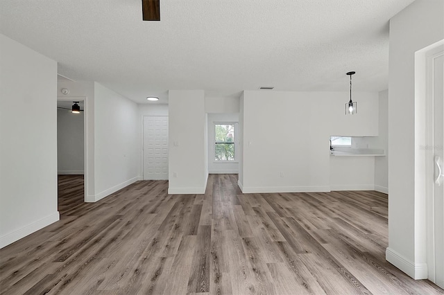 spare room with ceiling fan, a textured ceiling, baseboards, and wood finished floors