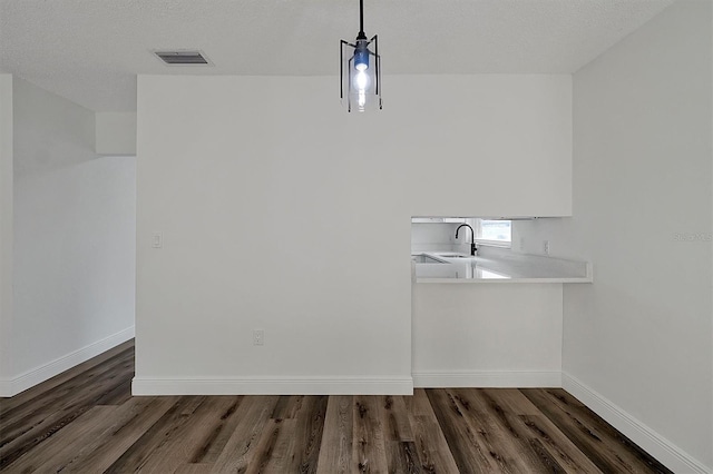 unfurnished dining area featuring dark wood-style flooring, visible vents, a sink, and baseboards