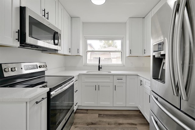 kitchen featuring stainless steel appliances, dark wood-style flooring, a sink, and white cabinets