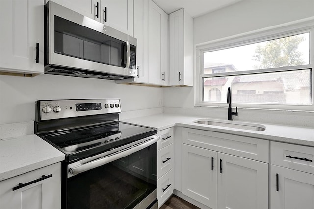 kitchen featuring white cabinets, light stone counters, stainless steel appliances, and a sink