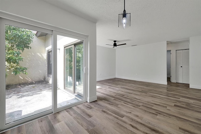 interior space featuring a textured ceiling, wood finished floors, a ceiling fan, and baseboards