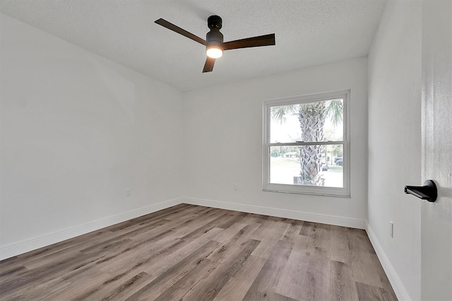 unfurnished room with a textured ceiling, ceiling fan, wood finished floors, and baseboards