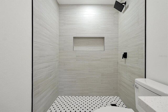 full bath featuring tiled shower and toilet