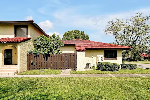 view of front of property featuring a front yard, fence, a tile roof, and stucco siding