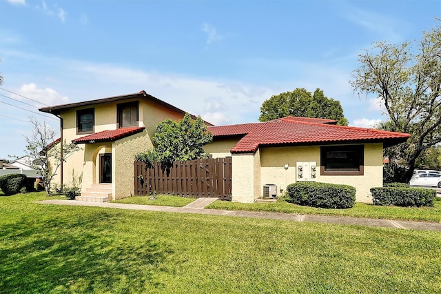 mediterranean / spanish-style house featuring a tiled roof, central AC unit, fence, and stucco siding