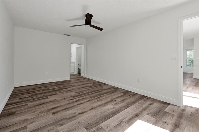 unfurnished room featuring ceiling fan, a textured ceiling, baseboards, and wood finished floors