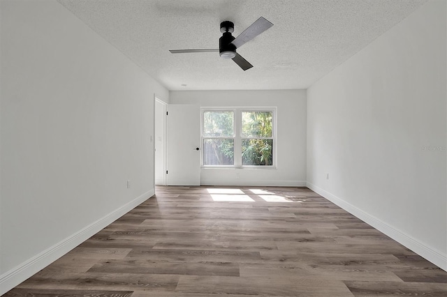 spare room with ceiling fan, a textured ceiling, baseboards, and wood finished floors