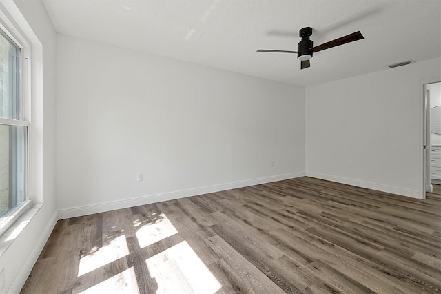 empty room featuring baseboards, visible vents, and wood finished floors