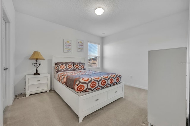 bedroom with light colored carpet and a textured ceiling