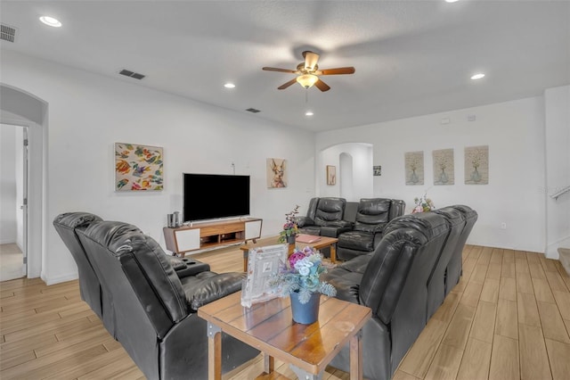 living room featuring ceiling fan, a textured ceiling, and light hardwood / wood-style flooring