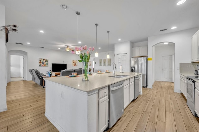 kitchen with appliances with stainless steel finishes, white cabinetry, sink, and a kitchen island with sink