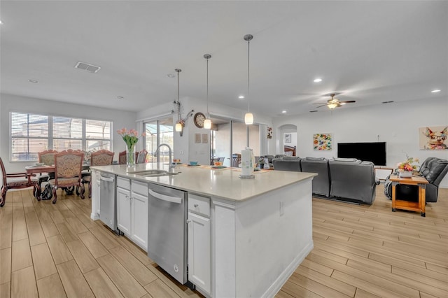 kitchen with dishwasher, sink, white cabinetry, hanging light fixtures, and a kitchen island with sink