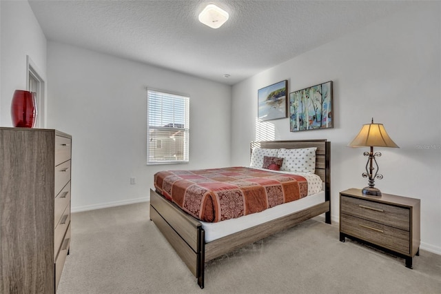 bedroom with light colored carpet and a textured ceiling