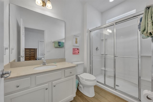 bathroom with an enclosed shower, vanity, wood-type flooring, and toilet