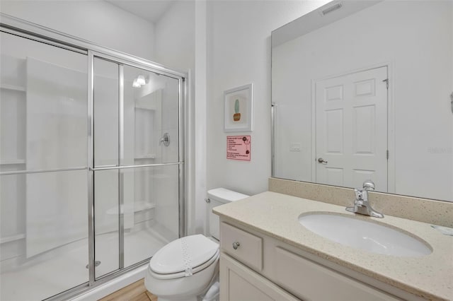 bathroom featuring an enclosed shower, vanity, wood-type flooring, and toilet