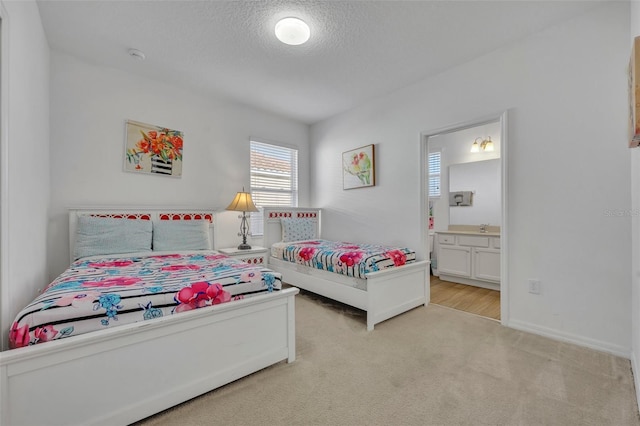 bedroom with ensuite bathroom, light colored carpet, sink, and a textured ceiling