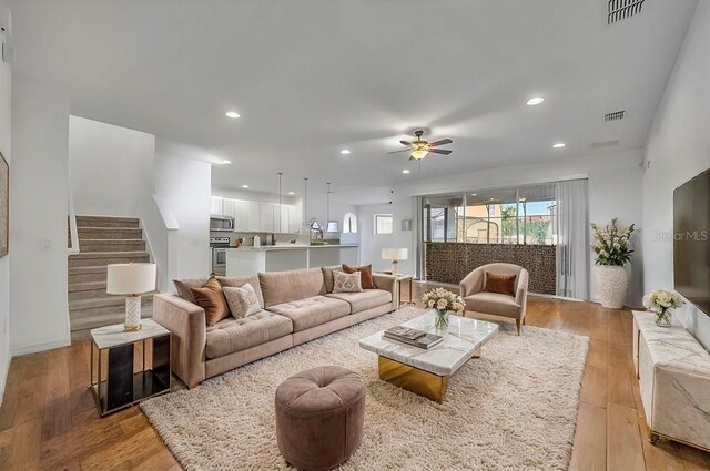 living area with stairs, light wood finished floors, visible vents, and recessed lighting