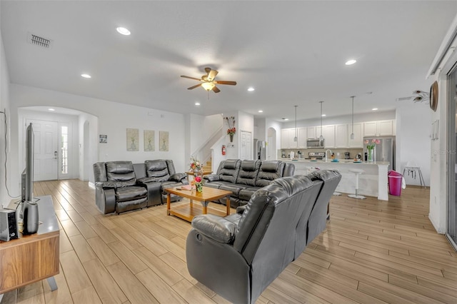 living area with arched walkways, visible vents, recessed lighting, and wood tiled floor