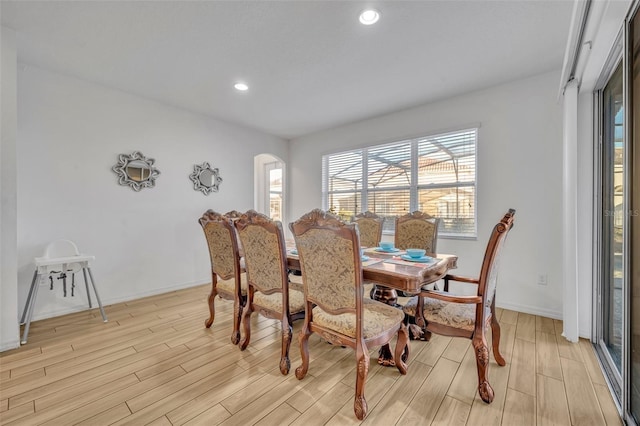 dining area with arched walkways, baseboards, light wood-style flooring, and recessed lighting