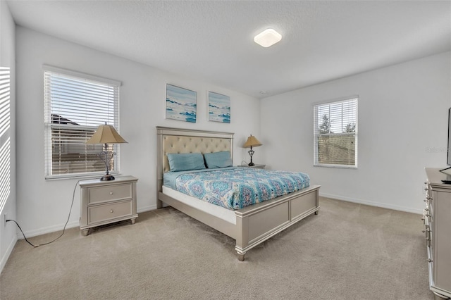 bedroom featuring light colored carpet, a textured ceiling, and baseboards