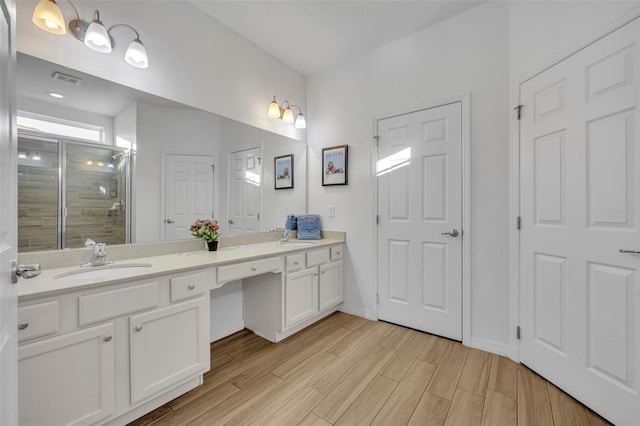 full bathroom featuring double vanity, wood finished floors, a sink, and a shower stall