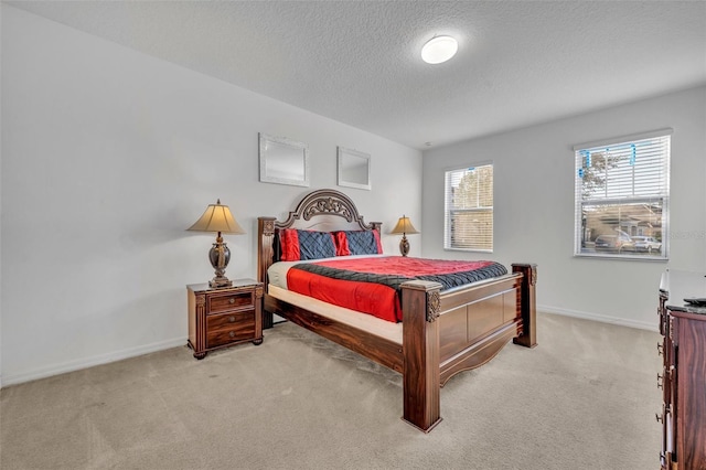 bedroom featuring light carpet, a textured ceiling, and baseboards