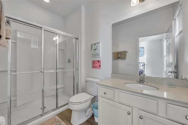 bathroom featuring toilet, a shower stall, wood finished floors, and vanity