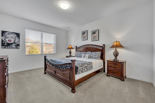 bedroom with light carpet, a textured ceiling, and baseboards