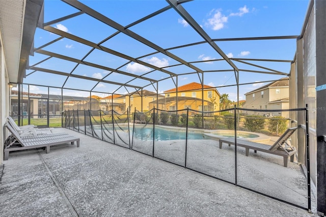 view of pool with glass enclosure, a pool with connected hot tub, a patio area, and a residential view