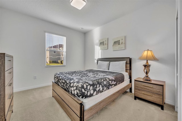 bedroom with baseboards, a textured ceiling, and light colored carpet