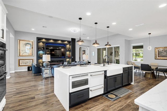 kitchen with pendant lighting, dark hardwood / wood-style flooring, sink, and white cabinets