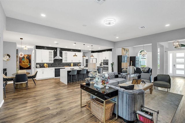 living room with beverage cooler, hardwood / wood-style floors, an inviting chandelier, and sink