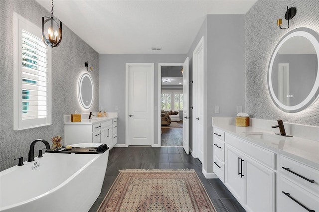 bathroom featuring a wealth of natural light, an inviting chandelier, wood-type flooring, and a washtub