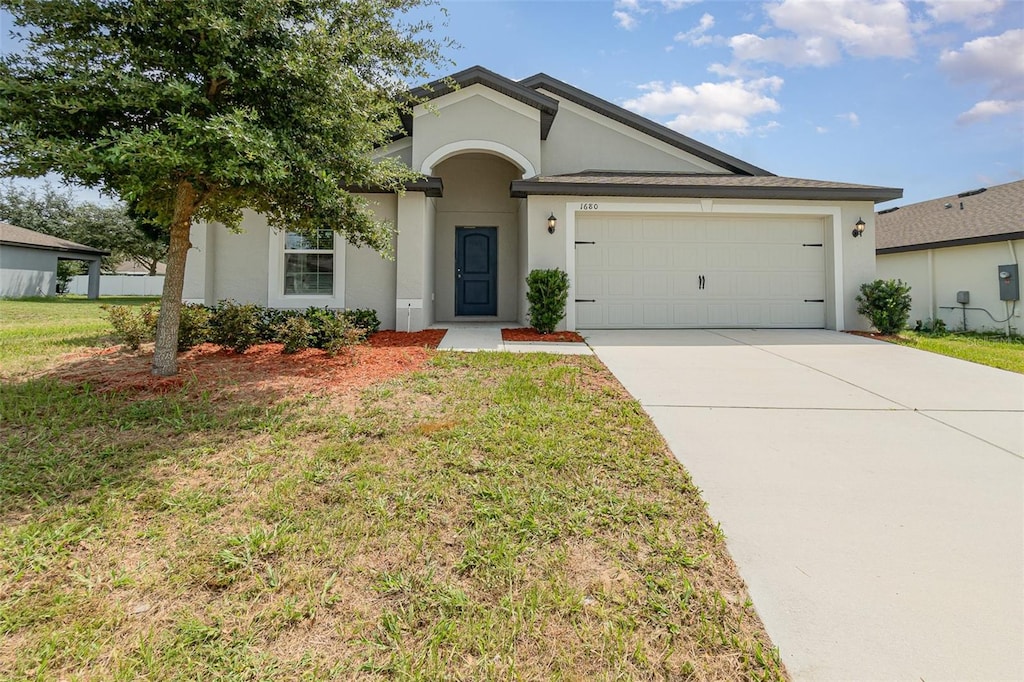 ranch-style home featuring a garage and a front lawn