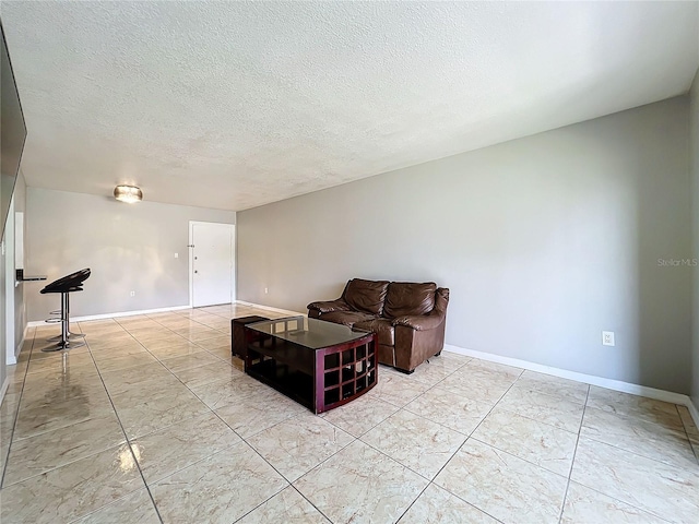 living area with a textured ceiling and light tile patterned flooring