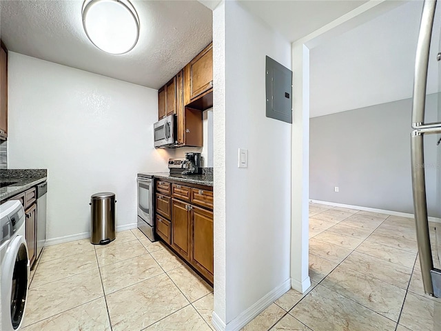 kitchen featuring appliances with stainless steel finishes, electric panel, washer / dryer, dark stone counters, and light tile patterned flooring