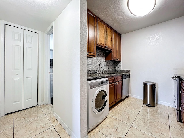 laundry area featuring light tile patterned flooring, sink, washer / dryer, and a textured ceiling