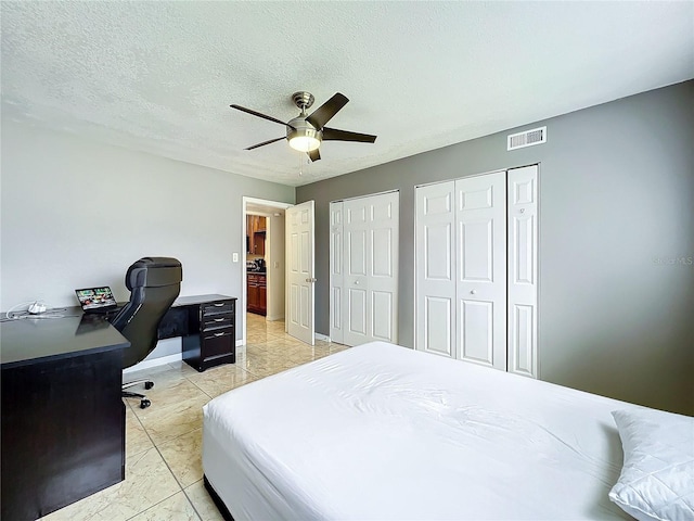 bedroom featuring a textured ceiling, ceiling fan, light tile patterned floors, and two closets